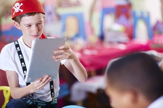 Boy dressed up as pirate using digital tablet on a party