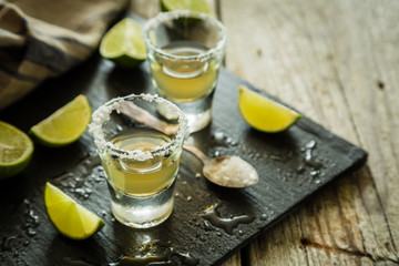 Gold tequila shots on rustic wood background