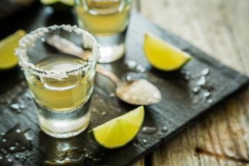 Gold tequila shots on rustic wood background