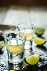 Gold tequila shots on rustic wood background
