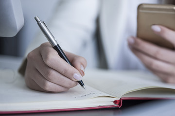 Close-up of woman at desk taking notes