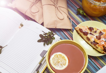 cherry pie, tea, glass jar of honey and other decorations on the colorful tablecloth
