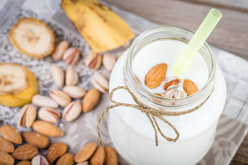 Banana and almond milk smoothie in a jar and mixed nuts on a rustic table