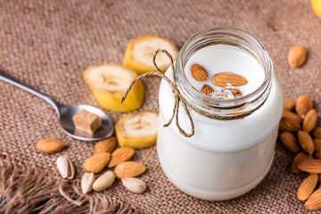 Obraz na płótnie Canvas Banana and almond milk smoothie in a jar on a burlap