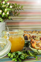cherry pie on the colorful tablecloth with green twig and honey