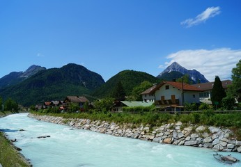 Milky white turquoise turbulent mountain river channelled through the German city Mittenwald at the foothills of the Alps.
