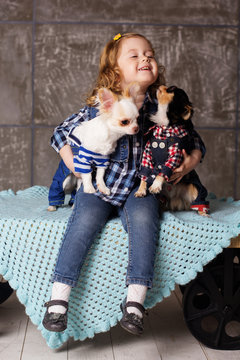 Girl is embraces two small chuhuahua dogs