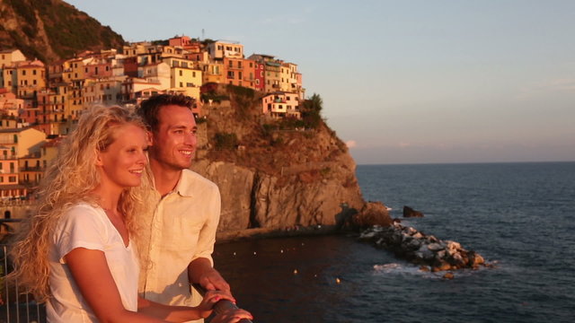 Couple in love by sunset on holidays travel. Romantic young beautiful couple enjoying ocean view romance. Young people, man and woman traveling on vacation in Manarola, Cinque Terre, Liguria, Italy