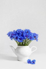 Beautiful bouquet of cornflowers in vase-teapot