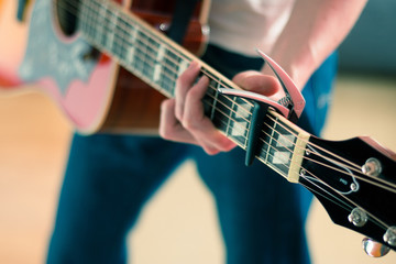 Gitarre spielen, Westerngitarre, Gitarrenhals mit Kapodaster, Person zu sehen