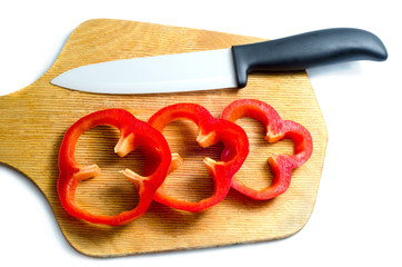 cut red bell a knife on a board on a white background