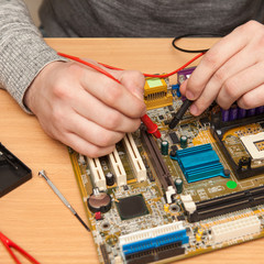 repairer is looking for the fault of the motherboard with a mult