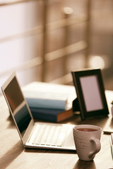 Stylish workplace with laptop and cup of tea in office
