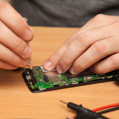 repairer to disassemble the smartphone. Hands close-up.