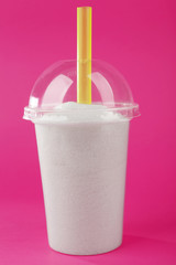 Plastic smoothie cup with granulated sugar and cocktail tube on pink background