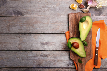 Sliced avocado with fresh basil on wooden cutting board