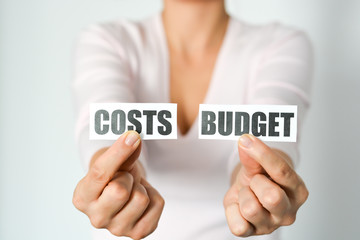 Budget planning concept with woman hands holding two printout with cost and budget words