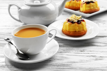 Tea with milk and cakes on wooden background