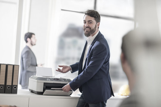 Smiling man in office using printer