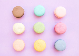 Sweet colorful French macaroon biscuits on pastel  lilac background