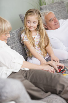 Senior woman and granddaughter playing together on sofa in living room