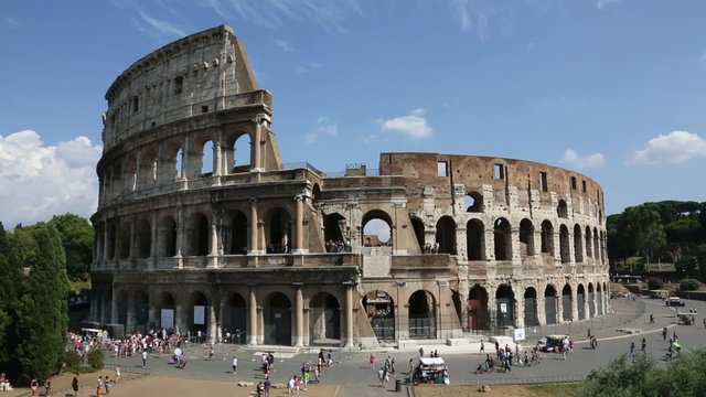 Colosseum, Rome, Italy. Timelapse of Roman Coliseum on summer day with blue sky. Beautiful view of the famous Italian landmark travel icon in the Roman forum.