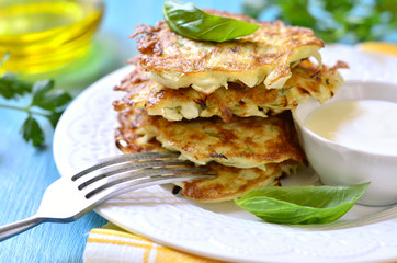 Cabbage fritters with cream sauce on a white plate.