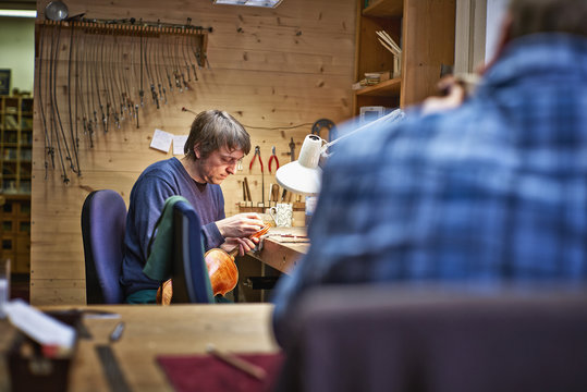 Violin maker in his workshop restoring a scroll