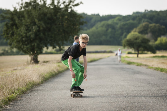 Boy skateboarding on a rural street - Powered by Adobe
