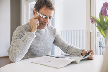 Man wearing optical head-mounted display reading a magazine