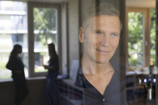 Portrait of smiling business man behind glass pane