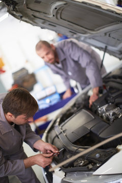 Two car mechanics at work in repair garage