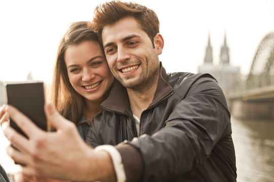Germany, Cologne, young couple taking selfie