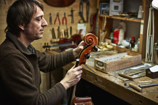 Violin maker in his workshop adjusting a cello mechanism