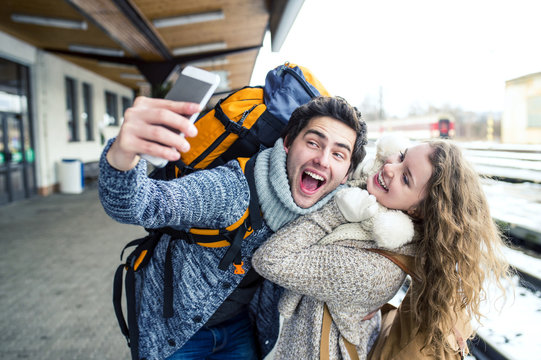 Playful young couple on station platform taking a selfie