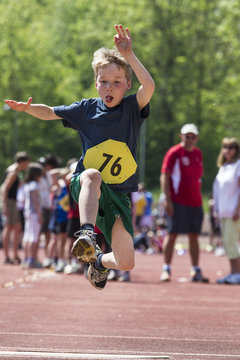 Germany, Munich, Boy long jumping on sports meeting