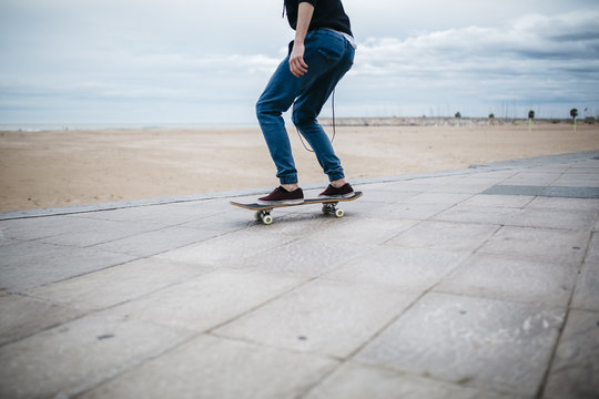 Spain, Torredembarra, young skateboarder in front of the beach, partial view