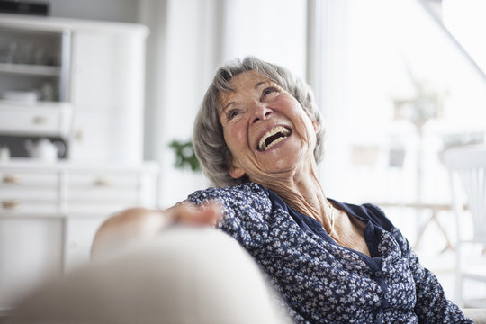 Portrait of happy senior woman sitting on couch at home