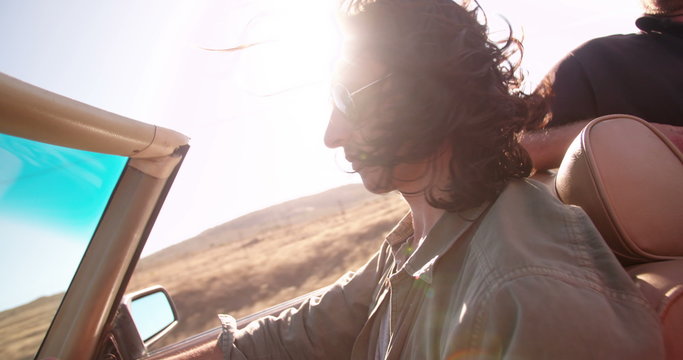 Hipster man driving a convertible and enjoys road trip