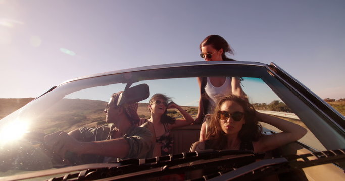 Group of happy young people on convertible car road trip