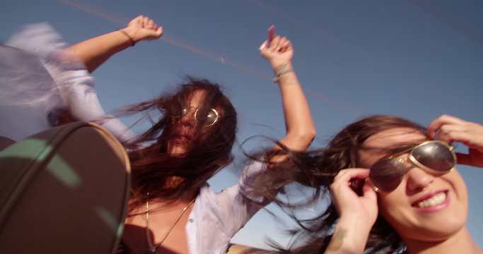Boho girls partying on the backseat of convertible car