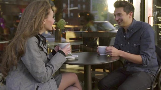 Handheld two shot of very cute couple laughing and having a conversation outside a cafe