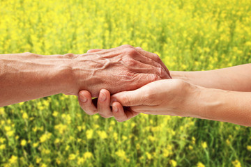 Hands of an elderly senior holding the hand of a woman