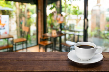 A Cup of coffee  on a rustic wooden table with coffee shop blurred background.