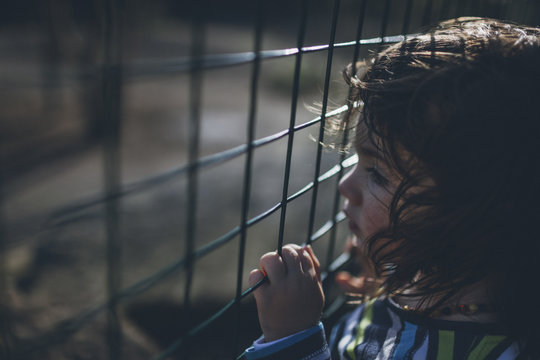 Serious boy behind fence