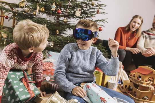 Brothers looking at new ski googles in front of Christmas tree