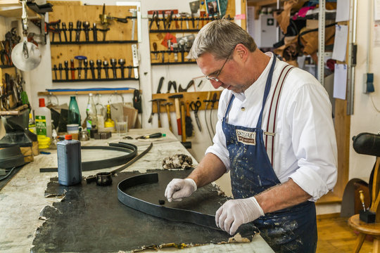 Saddler dyeing edges of leather strap with leather paint