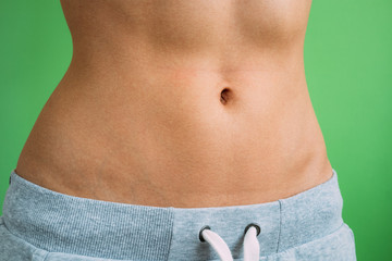 Close up of Belly slim girl in sweat pants on a green background