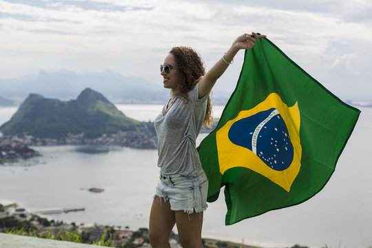 Brazil, woman with Brazilian flag on a viewpoint in Rio de Janeiro