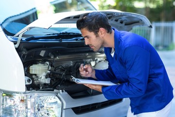 Male mechanic examining engine